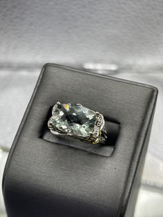 A dazzling 8 carat Blue Obsidian stone cut in a checkerboard pattern set with 75 pts of diamonds.  The ring is beautifully designed in 14 karat solid white gold with an ornate diamond setting throughout the outside of the ring. TDW:  0.75 cts Weight:  5.3 grams Size:  5 ½  Our Price $1500.00 Regularly Priced At $1900.00 Please See Our Video Remember - If you're purchasing for yourself or a gift for a loved one, buy with confidence.  We Guarantee Everything We Sell!  SKU # R948 Luxury Diamond Cut Gemstones For Formal Occasions, Luxury Diamond Gemstones For Formal Occasions, Luxury Gemstones With Diamond Accents, Luxury Cushion Cut Diamond Topaz Ring, Luxury Diamond Topaz Ring With Cushion Cut, Luxury Diamond Gemstones With Prong Setting, Luxury Topaz Ring With Diamond Accents, Luxury Diamond Ring With Gemstone Accents For Anniversary, Luxury White Gold Diamond Ring With Gemstone Accents