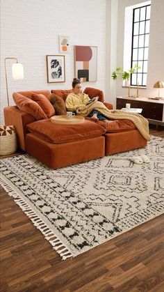 a man sitting on top of a couch in a living room next to a rug