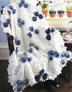 a white and blue blanket sitting on top of a chair next to a potted plant