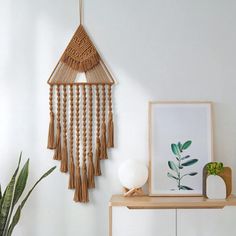 a white room with a plant and some pictures on the wall next to a shelf