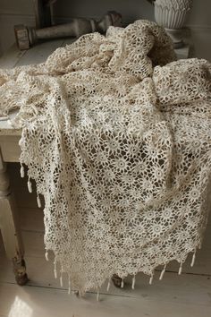 an old table with a white crocheted blanket on it