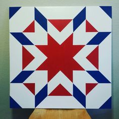 a red, white and blue star quilt on a wooden stand