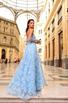 a woman in a blue dress is standing on some steps