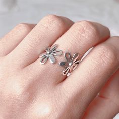 This dainty nature inspired floral ring is entirely made of 925 sterling silver, featured with two daisy flowers. Lovely on its self or stacked with other rings, it is designed to connect your personal expression with self-identity that goes far beyond. Fantastic to give as a gift or to simply treat yourself... ⭐️ ⇩⇩ PRODUCT INFO ⇩⇩ ⭐️ ► Metal: 925 sterling silver with hallmark (nickle free) ► Initial Band Diameter: approx 17.5 mm (UK Size O) ► Open band: adjustable to fit your size ► Hypoallergenic, comfortable to wear ♻️ Eco-Packaging: beautifully wrapped up inside a Kraft box, ready for gift giving! 🌟 GIFTING DIRECT!  FREE GIFT WRAPPING  Just simply mark your order as gift and leave your gift message. No invoices or receipts are included, I will hand write your message within a handmad Delicate Flower Shaped Ring For Spring, Delicate Flower Ring For Spring, Adjustable Delicate Flower Promise Ring, Spring Flower Promise Ring, Dainty Flower Rings For Spring, Spring Promise Ring With Open Ring Shape, Spring Promise Ring With Open Design, Spring Open Ring For Promise, Flower Shaped Anniversary Rings For Spring