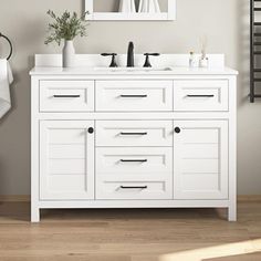 a white bathroom vanity with two sinks and mirrors on the wall next to a towel rack