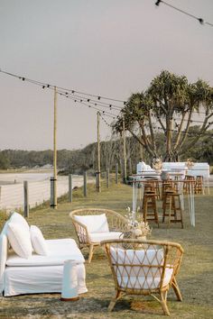 an outdoor setting with wicker furniture and string lights strung over the grass, along with tables and chairs