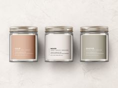 three jars with labels on them sitting next to each other in front of a marble wall