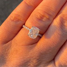 a woman's hand holding an engagement ring with a diamond in the middle and a band around it