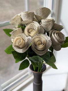 a vase filled with paper roses sitting on top of a window sill