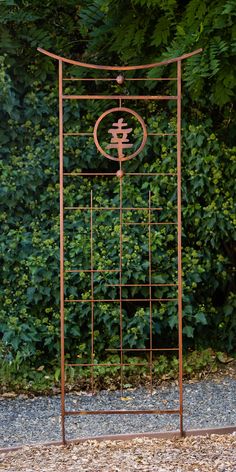 an iron garden trellis stands in front of some bushes and shrubbery on the ground