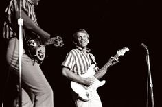 two men are playing guitars and singing into microphones while standing next to each other