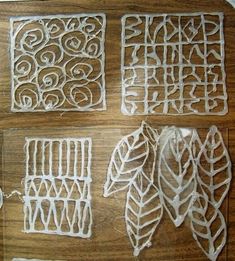 four pieces of carved paper sitting on top of a wooden table