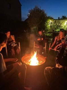 people sitting around a fire pit at night