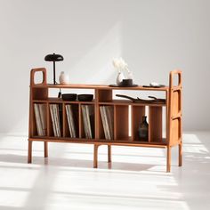 a wooden shelf with books and vases on it in front of a white wall