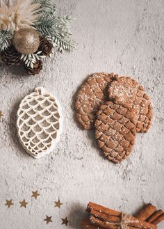 cookies and cinnamon sticks on a white surface with pine cones, star decorations and evergreen branches