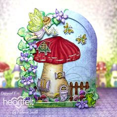 a card with an image of a mushroom house and fairy on the roof, surrounded by flowers