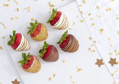 four strawberries are arranged on a white plate with gold confetti and sprinkles