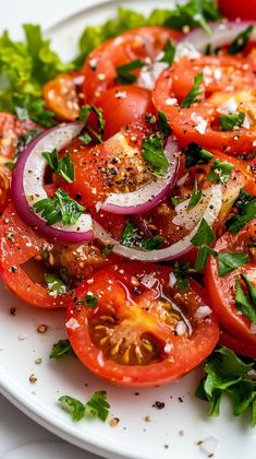 a white plate topped with tomatoes, onions and parsley on top of a bed of lettuce