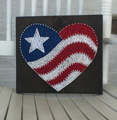 a patriotic heart with the american flag painted on it is sitting on a wooden bench