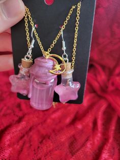 Add a touch of enchantment to your style with this charming Magic Shimmer Potion Bottle Necklace and Earring Set! This whimsical pendant features a miniature glass bottle filled with sparkling shimmer potion, capturing the essence of magic and mystery. The glass bottle is securely sealed and suspended from a dainty chain, perfect for adding a hint of mystical allure to any outfit. Whether you're a lover of fantasy or simply appreciate unique jewelry, this set is sure to bring a touch of magic to your day. Perfect for cosplay or ren faire accesories! ONE OF A KIND PIECE PLEASE NOTE I MAY NOT BE ABLE TO RECREATE THIS SPECIFIC COLOR! (If You Love it.. Get it now!) ;) Each necklace set is a handmade treasure and  truly ONE OF A KIND!  Chains (22.5" long) with easy to use clasps. 925 Sterling S Potion Bottle Earrings, Pink Spiritual Charm Necklace For Gift, Spiritual Pink Charm Necklace As Gift, Spiritual Pink Charm Necklace For Gift, Handmade Magical Charm Necklaces For Gifts, Handmade Mystical Pink Jewelry, Pink Handmade Mystical Jewelry, Pink Mystical Handmade Jewelry, Enchanting Gold Jewelry For Gifts