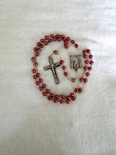 This listing is for a lovely, heavy quality, vintage Catholic Rosary with red metal plated beads.  The beads and the brass color chain do not attract a magnet.  The cross and connecting piece that features a portrait of Mother Mary holding Jesus is brass colored on the front side, but silver in color on the back and lightly attracts the magnet so I am unsure what the rosary is made of.  Due to its near perfect condition I do not believe it was ever used.  It is  unmarked, but most of the rosaries I got in the collection this came in dated from the early 1990's thru the early 2000's.  This is a wearable rosary with a 28" necklace portion and a 7" drop to the bottom of the Crucifix.  It is in beautiful condition fresh from an estate....so you can use it for prayers as well.  No missing beads Mary Holding Jesus, Jewelry Display Box, Catholic Rosary, The Rosary, Rosary Catholic, Mother Mary, Jesus Is, Brass Color, Metal Beads