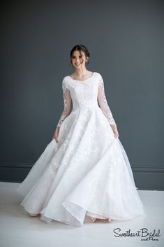 a woman in a white wedding dress posing for the camera with her hands on her hips