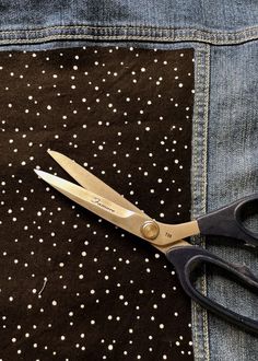 a pair of scissors sitting on top of a black and white polka dot fabric with holes in it