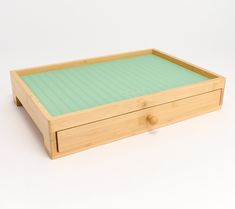 a small wooden box with two drawers on the bottom and one drawer open to show something green