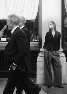 a man and woman walking down the street in front of a store with their hands on their hips