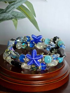 This bracelet is uniquely handmade. It includes semi-precious stones blue sandstone, Quartz, crystal, glass, and a starfish charm. This is an easy-to-wear bracelet with no clasp just wrap around your wrist. This bracelet is made to fit most wrists because there is no clasp making it adjustable to each individual wrist. Add a touch of elegance and style to your outfits with our double wire bracelet. Made with high-quality materials, this versatile accessory is perfect for any occasion. Upgrade your accessory game and enhance your look with this stunning bracelet today! wonderful gift for yourself or others. Adjustable Czech Glass Bracelets For Beach, Blue Wire Wrapped Bracelets, Unique Blue Wire Wrapped Bracelets, Handmade Czech Glass Bracelets For Beach, Unique Blue Wire-wrapped Bracelets, Blue Czech Glass Bracelets For Beach, Blue Czech Glass Bracelet For Beach, Blue Czech Glass Beach Bracelet, Blue Natural Stones Bracelets For Beach