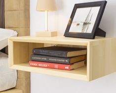 books are stacked on top of each other in front of a lamp and framed photograph