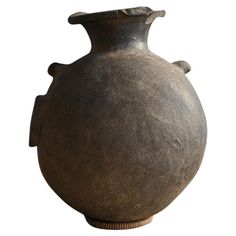 a large brown vase sitting on top of a wooden stand