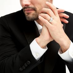 a man in a black suit and white shirt wearing a diamond ring