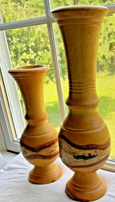 two yellow vases sitting next to each other on a window sill