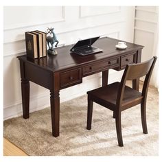 a wooden desk with a laptop on top of it next to a chair and books