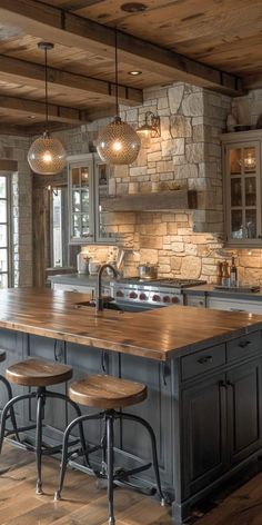 a large kitchen island with stools in front of it and lights hanging from the ceiling