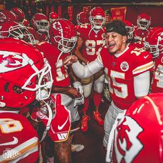 a group of football players standing next to each other in a locker room with helmets on