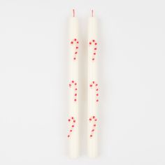 two white candles with red dots on them