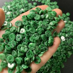 a person holding green beads in their hand