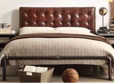 a bed with a brown leather headboard and foot board next to a basket on the floor