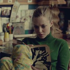 a woman sitting at a table reading a book