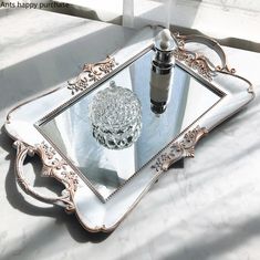 an ornately decorated tray with a bottle and glass container on the bottom, sitting on a marble surface