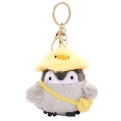 a small stuffed animal with a yellow hat on it's head and two penguins