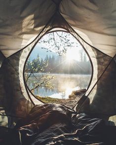 a tent with the sun shining through it's window and water in the background