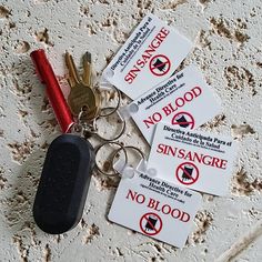 four key chains with no blood labels on them sitting next to a pair of keys