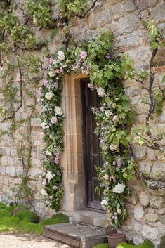 an old stone building with ivy and flowers growing on it's side window sill