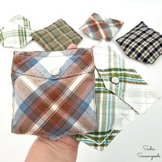 four different colored plaid shirts are being held up by someone's hand with their fingers