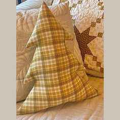 two pillows on a bed with white sheets and brown plaid patterns, one has a star in the middle