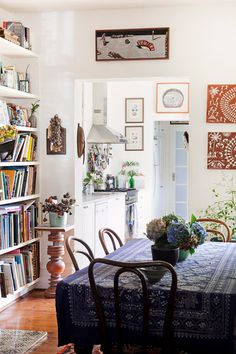 a dining room table and chairs in front of a book shelf with books on it