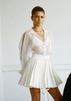 a woman in a white shirt and pleated skirt